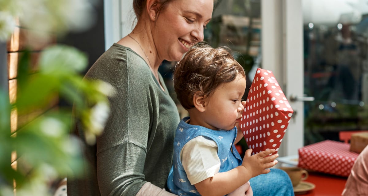 A parent and toddler opening a wrapped gift together