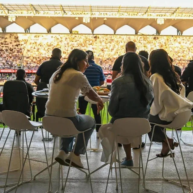 Guests dining at tables overlooking a packed stadium