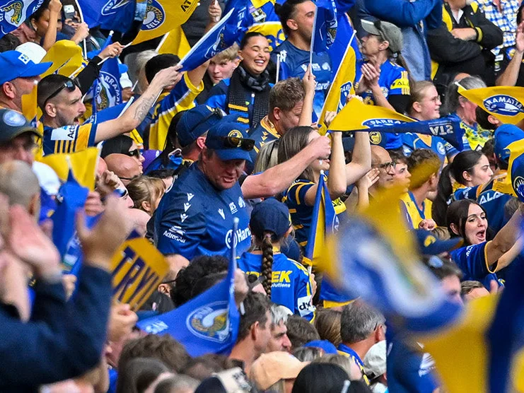 Eels fans waving blue and gold flags in the crowd